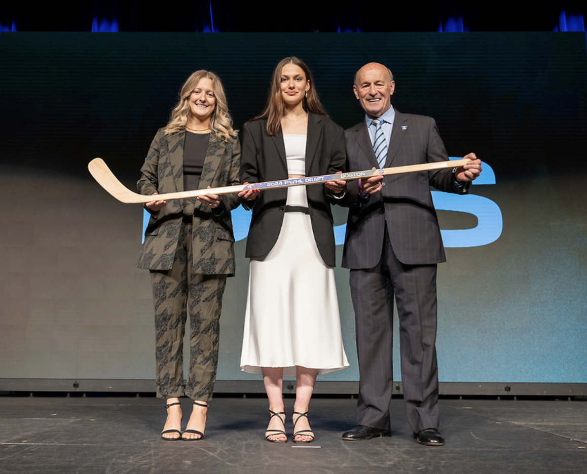 From left to right: Marmer, Pejšová and Kasten pose on stage holding a wooden PWHL Boston draft stick.