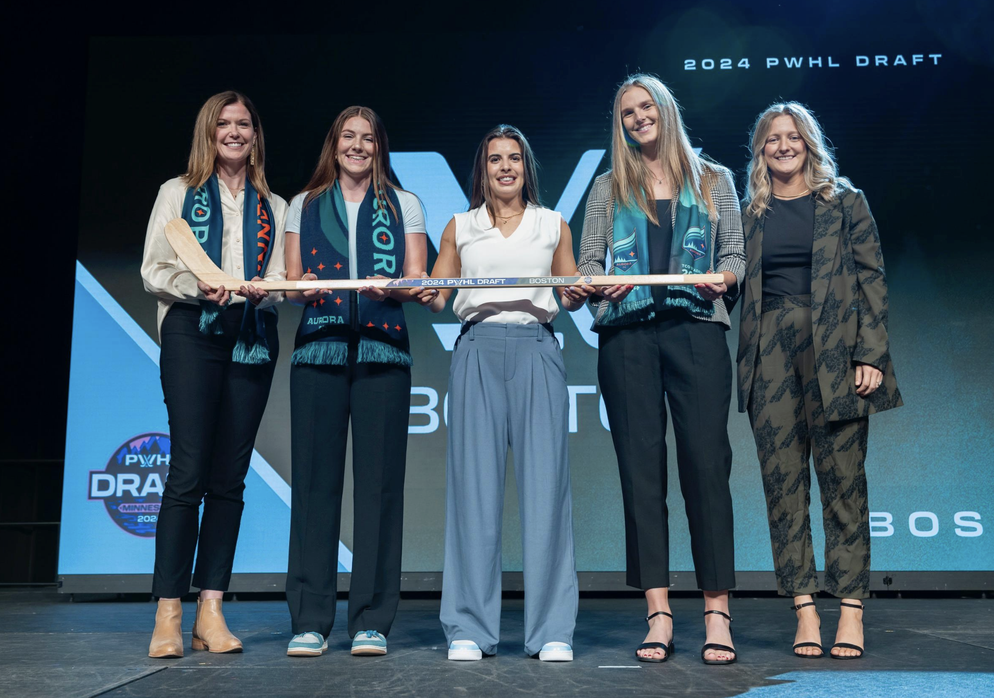 Bard poses with a draft stick on stage alongside family and Marmer. Bard is the middle, with two people on each side of her. Marmer is on the far right.