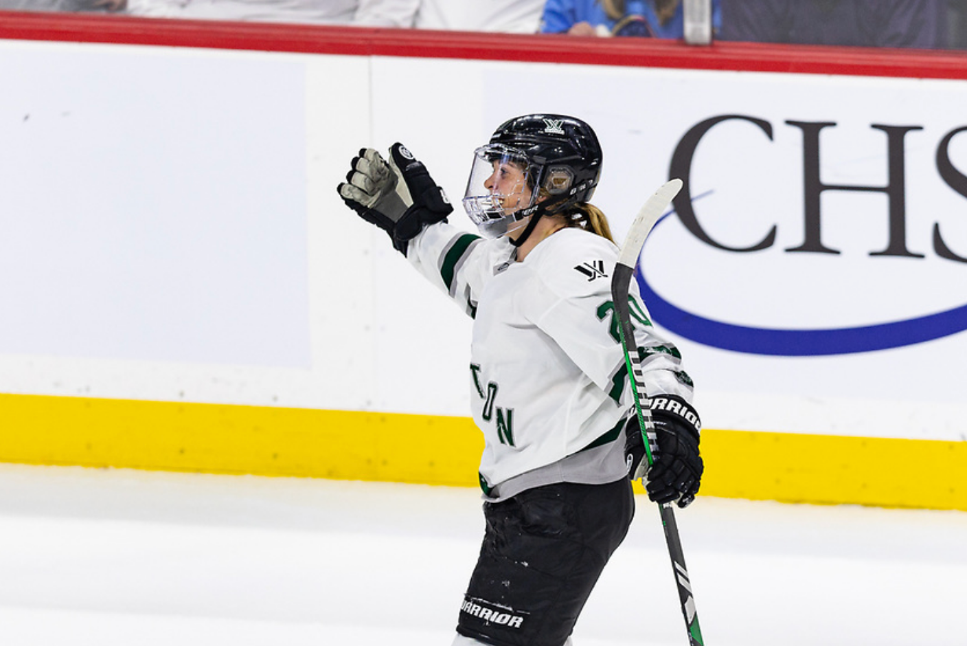 Brandt opens her arms for a hug to celebrate a regular season win over Minnesota. She is wearing a white away jersey.