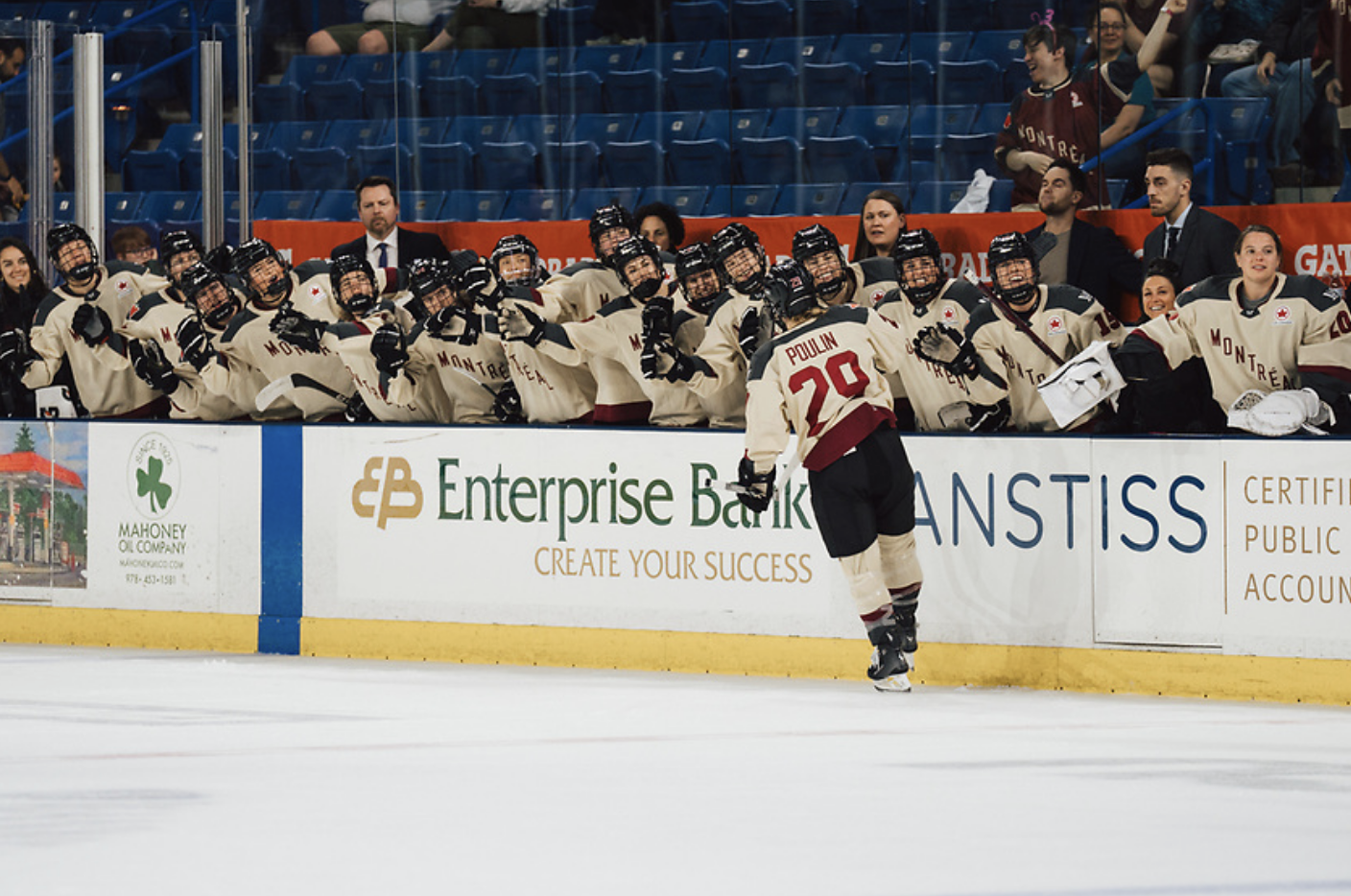 Poulin skates down the bench for fist bumps after scoring a playoff goal. They are all wearing cream away jerseys.