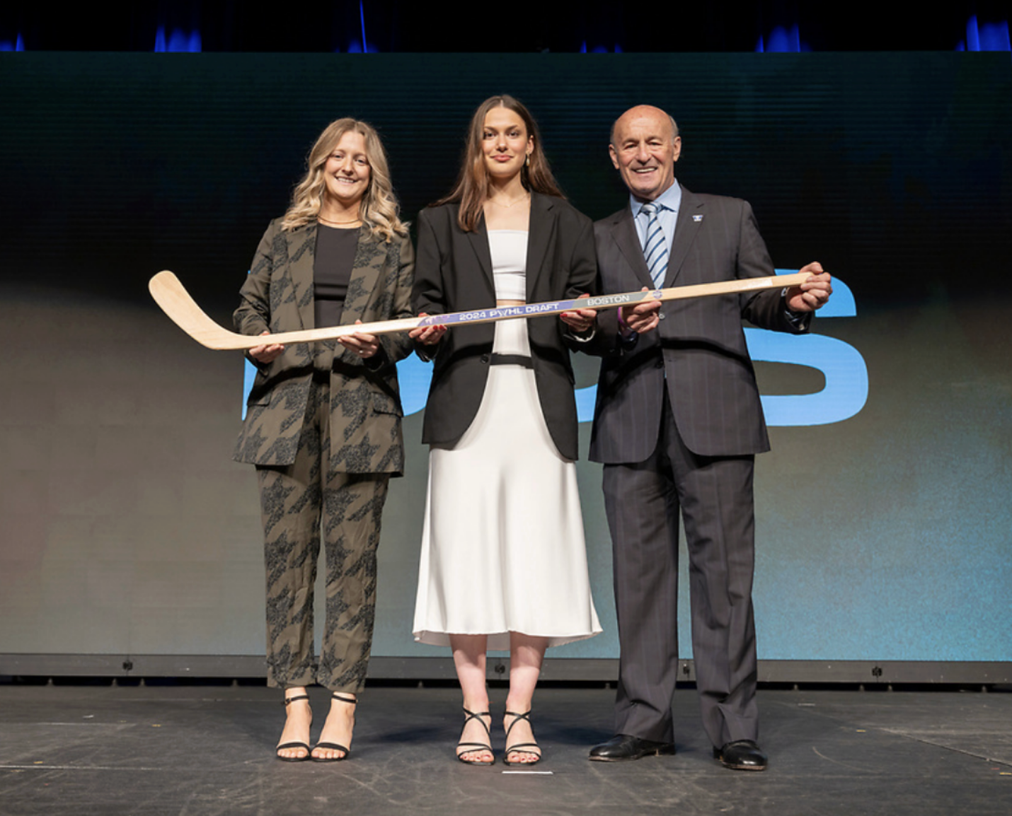 From left to right: Marmer, Pejšová, and Kasten hold a wooden stick and smile at the camera. 