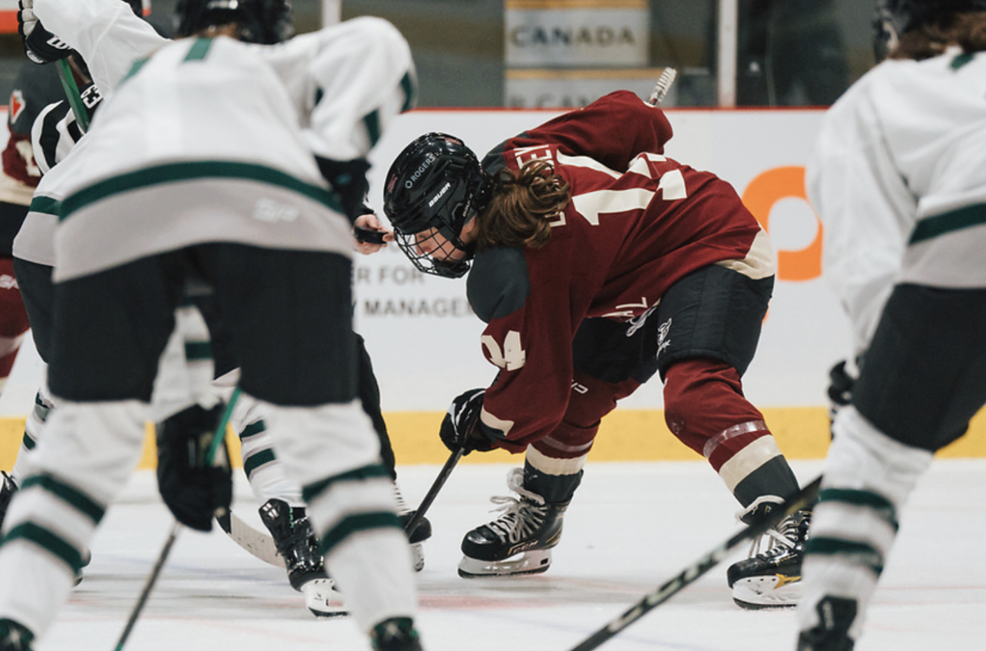 Dempsey, wearing a maroon Montréal uniform, crouches and watches the puck in the referees hand in prepartion for a faceoff. 