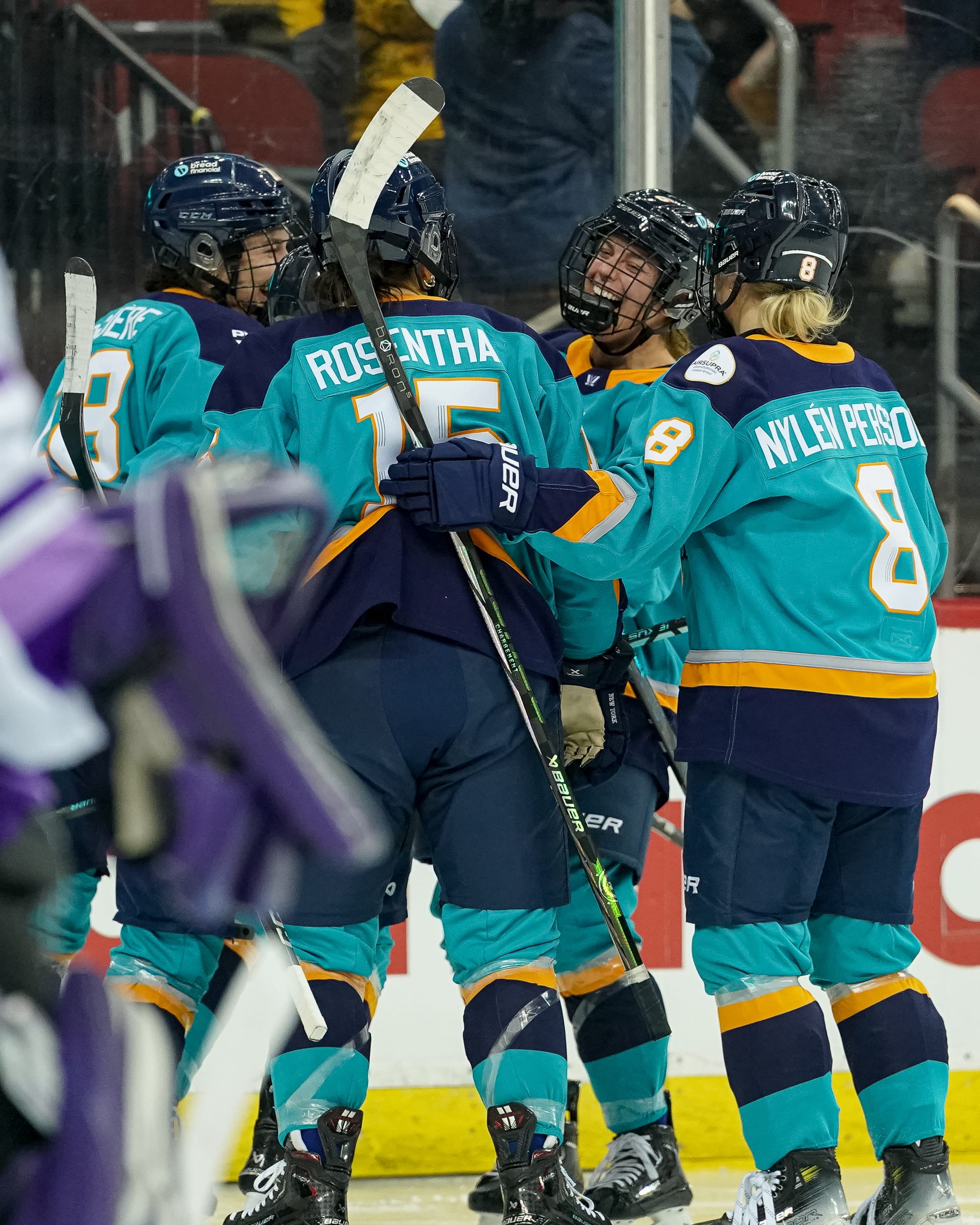 Sirens players celebrate a goal with a group hug. They are wearing teal home uniforms.