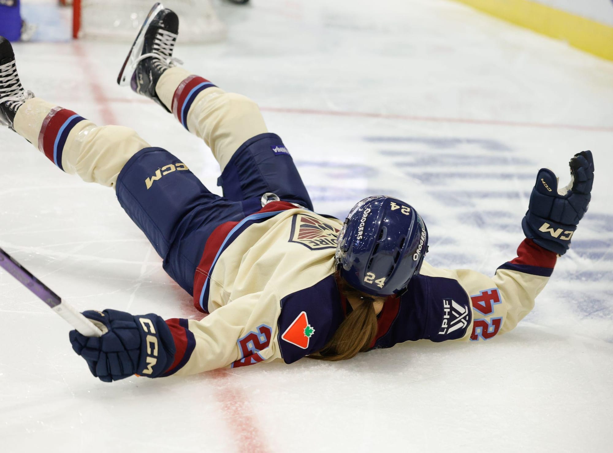 Boreen lays on her back with her arms above her head. She is off to the side of the net and has just scored. She is wearing a cream away uniform.