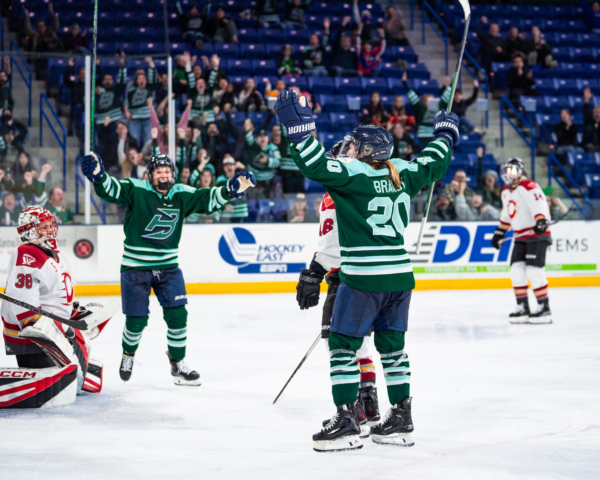 Brandt raises her arms in celebration. In the background, another Fleet player does the same. They are wearing green home uniforms.