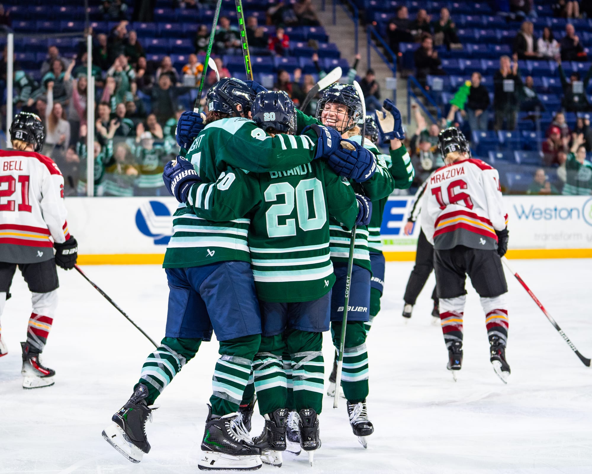 Fleet players celebrate a goal with a tight group hug. They are wearing green home uniforms.