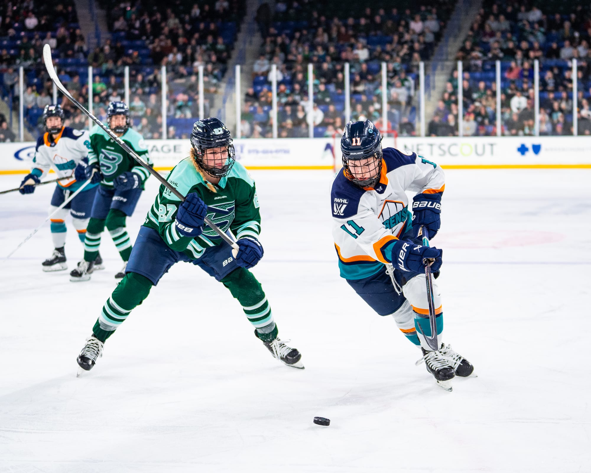 Maloney (left in green) raises her stick as she prepares to knock the puck away from Roque (right in white). 