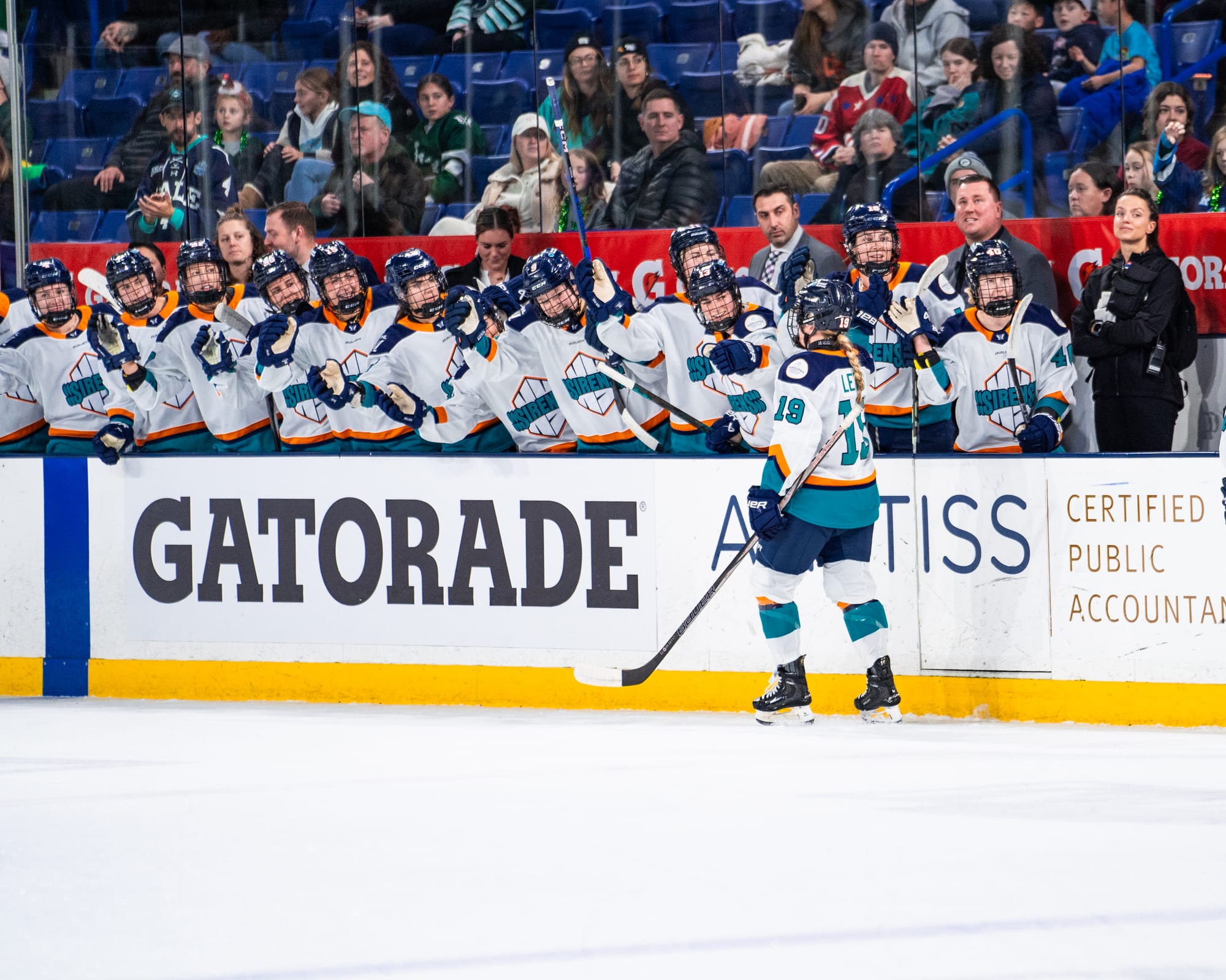 Levis skates down the handshake line at the bench. She is side-to the camera and wearing a white away uniform.