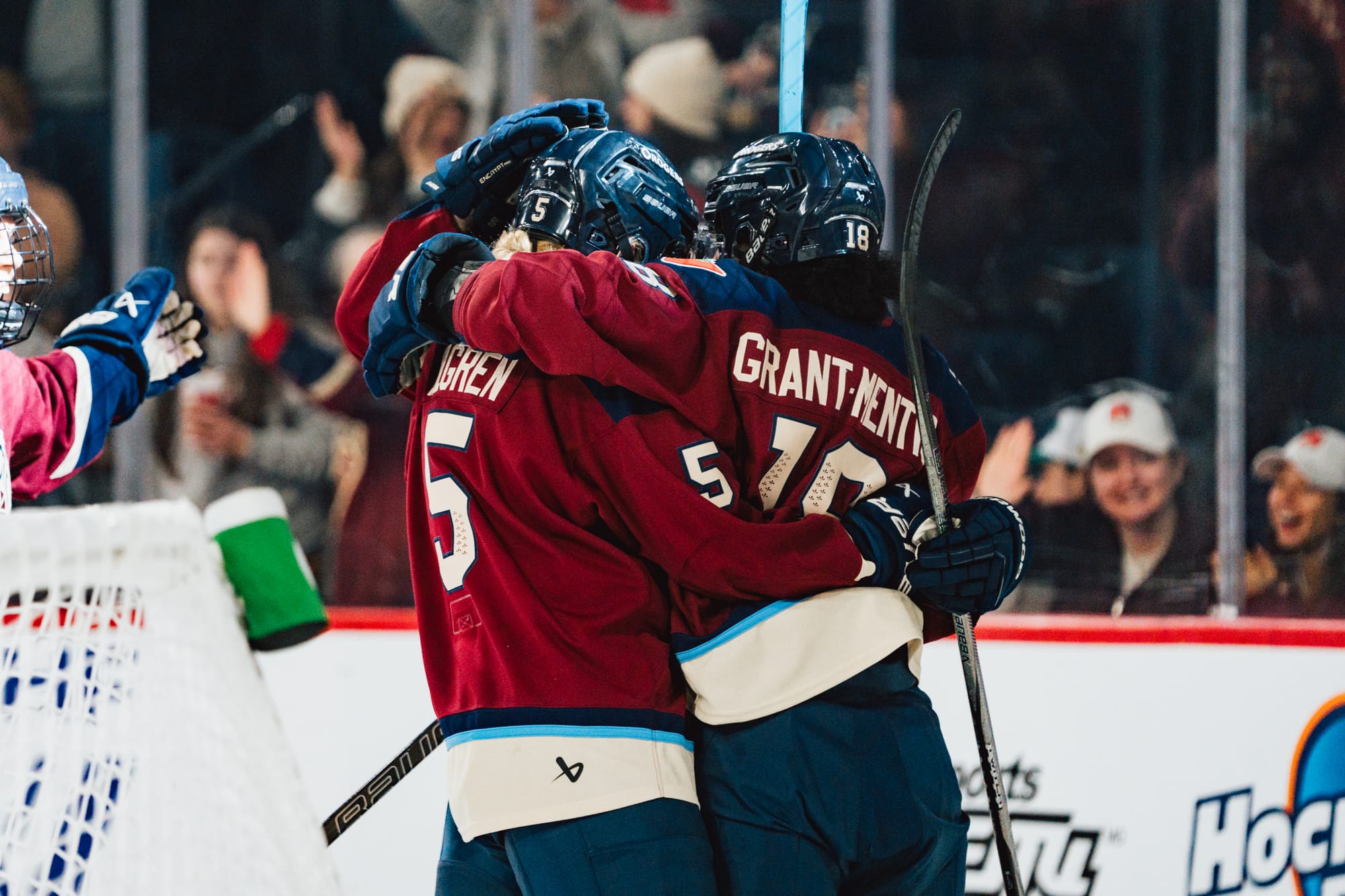 Montréal players celebrate a goal with a tight group hug. They are wearing maroon home uniforms.