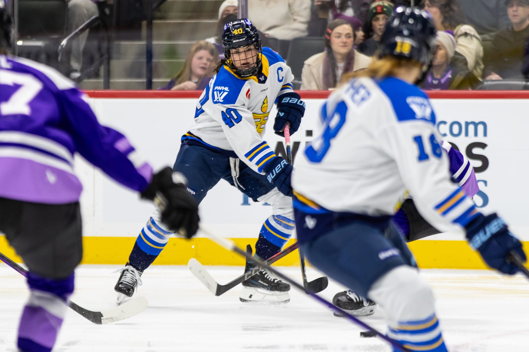 Turnbull looks up as she makes a pass to Jesse Compher, who is in the frame but out of focus. They are both wearing white away uniforms.