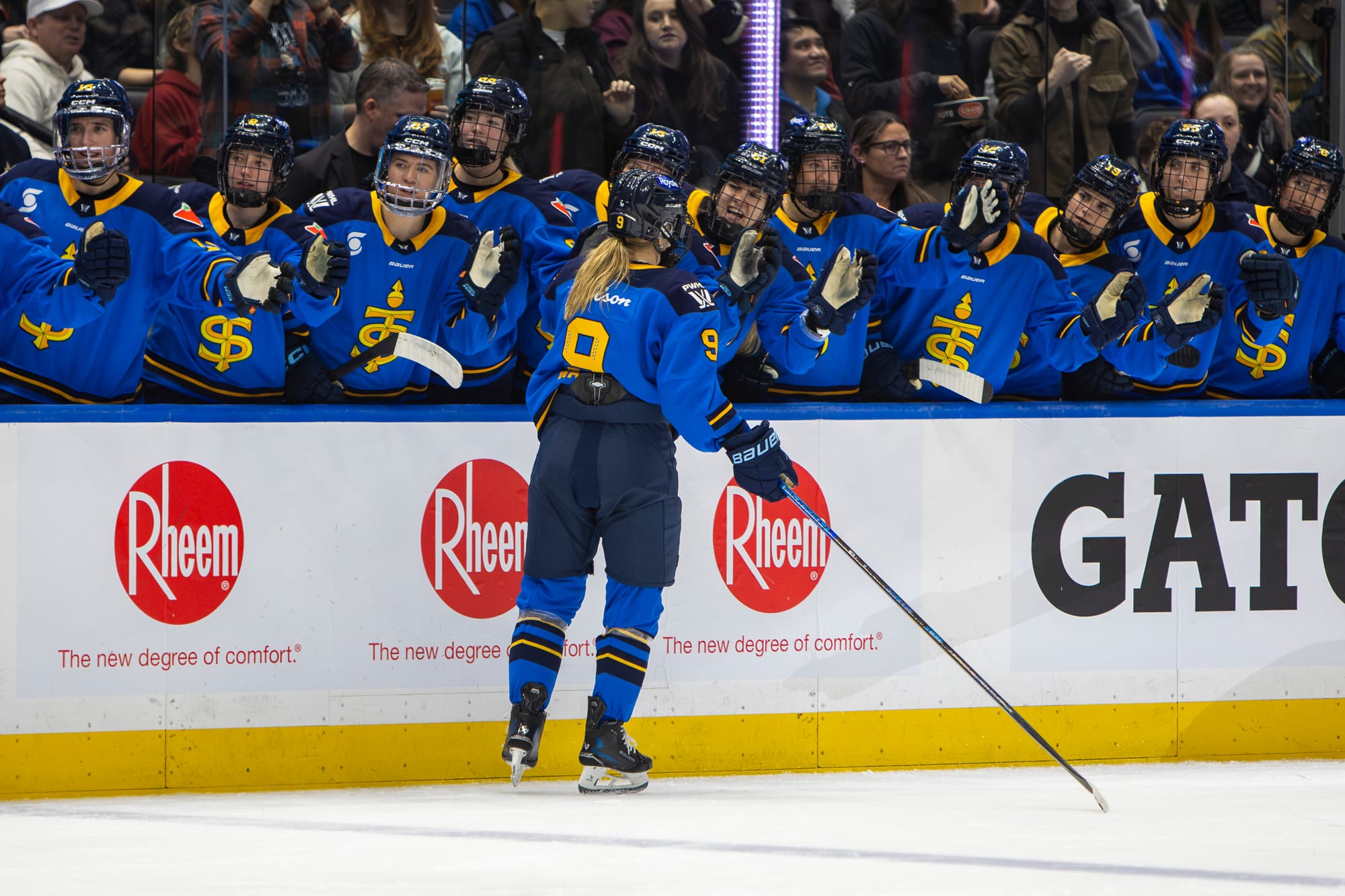 Watts skates down the handshake line at the bench. She is wearing a blue home uniform.