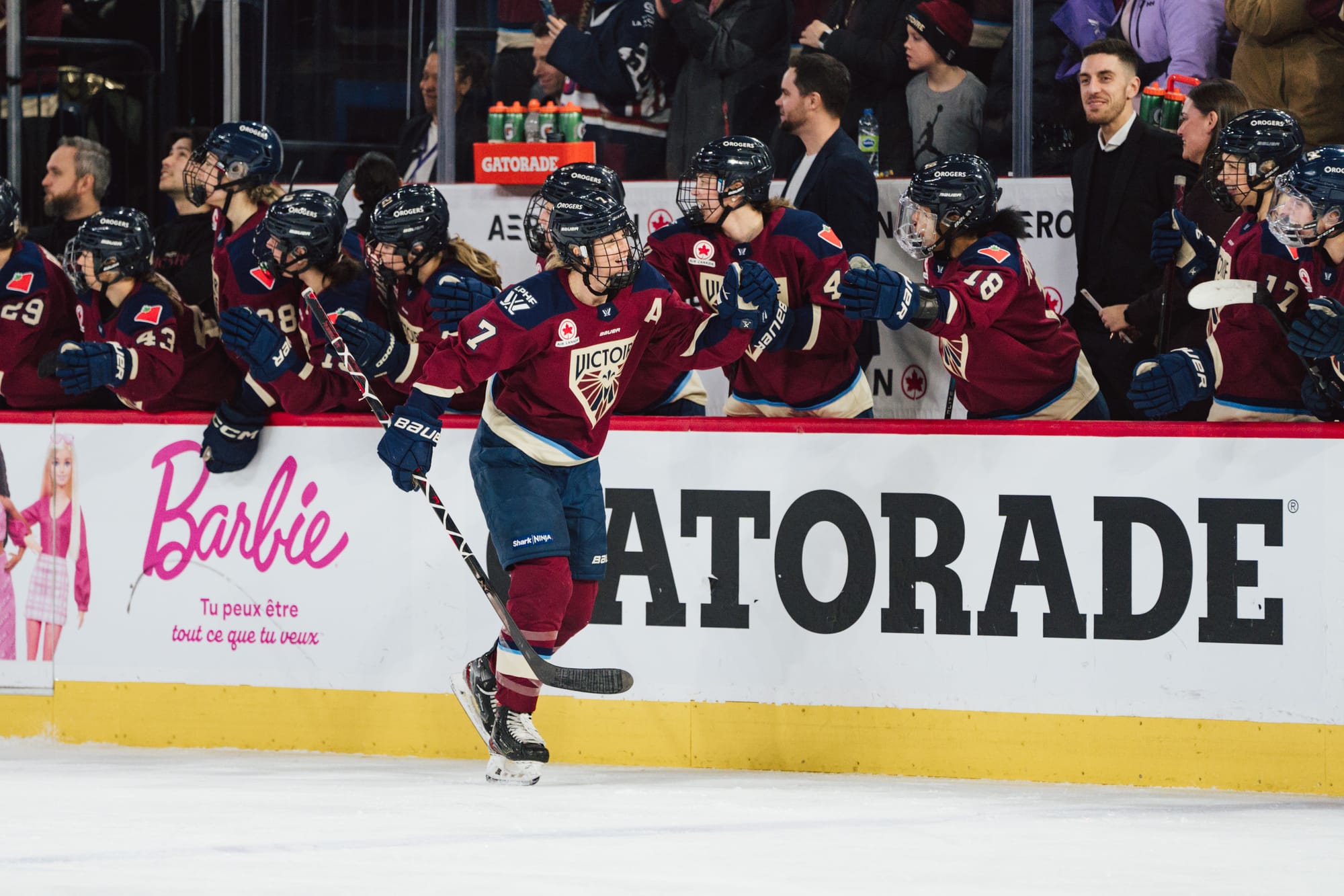 Stacey skates down the handshake line at the bench. She is wearing a maroon home uniform.