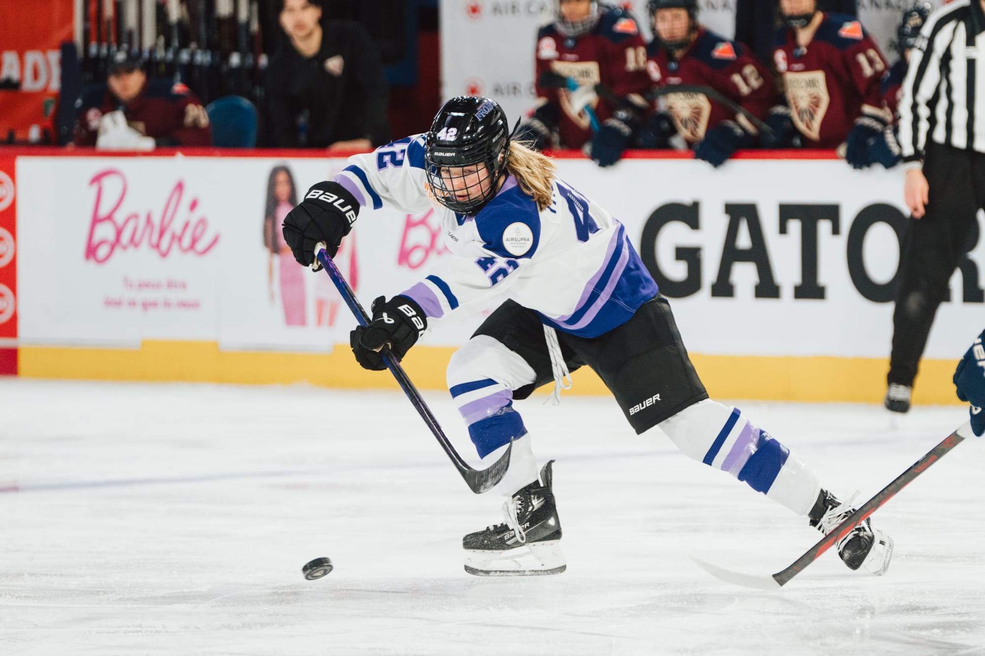 Thompson turns to her right to make a pass along the blueline. She is wearing a white home uniform.