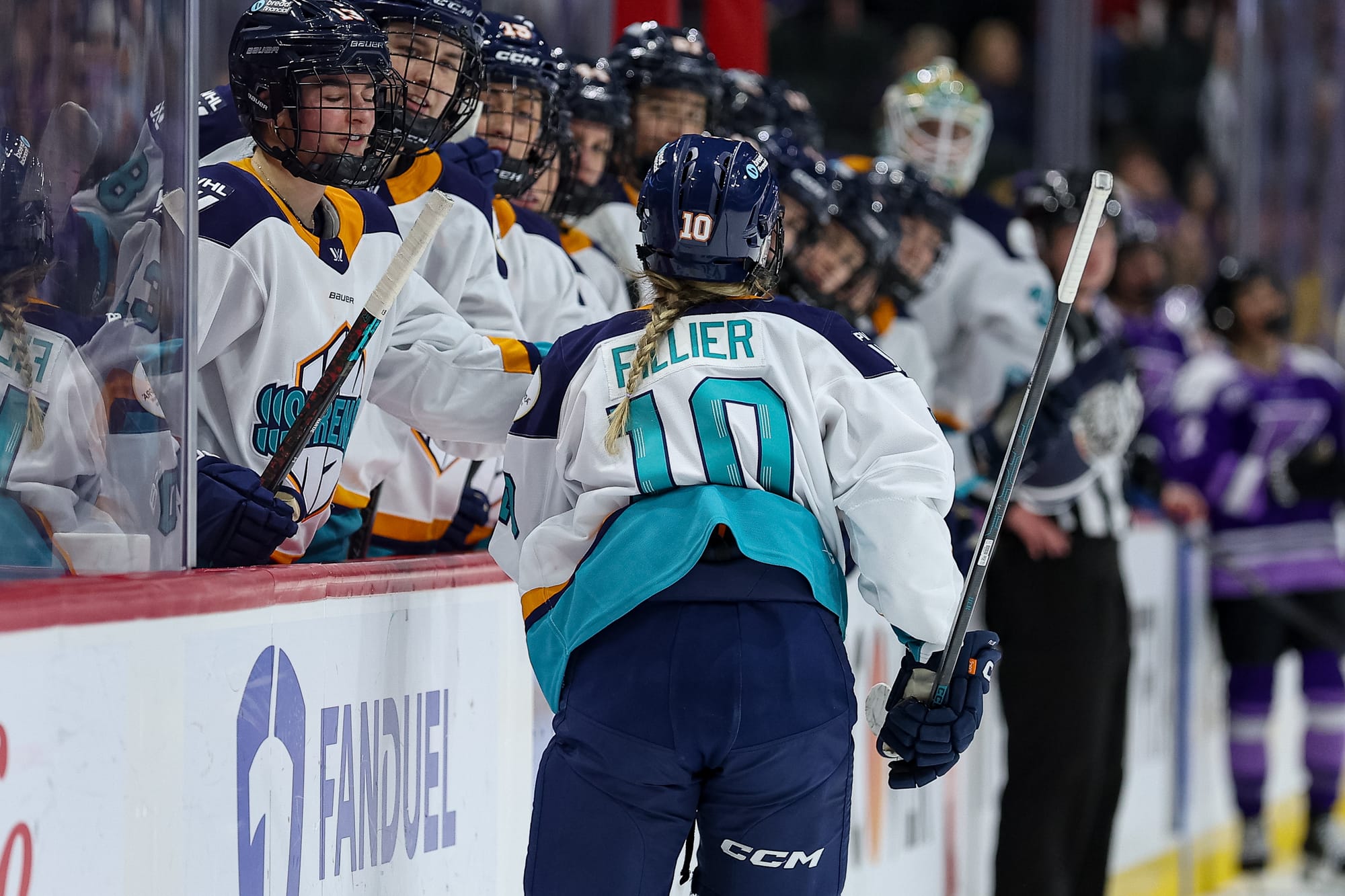 Fillier skates down the handshake line at the bench. Her back is to the camera, and she is wearing a white away uniform.