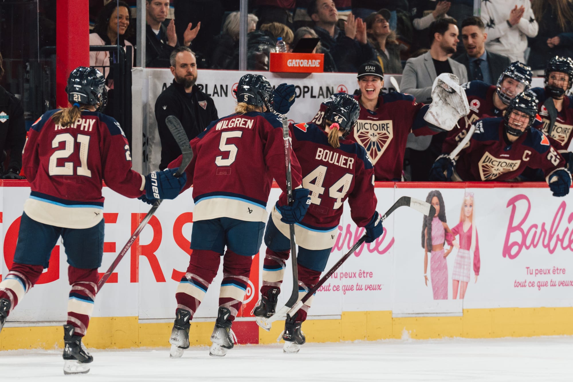 Three Montréal players are about to skate down the celebratory handshake line at the bench. They are wearing maroon home uniforms.