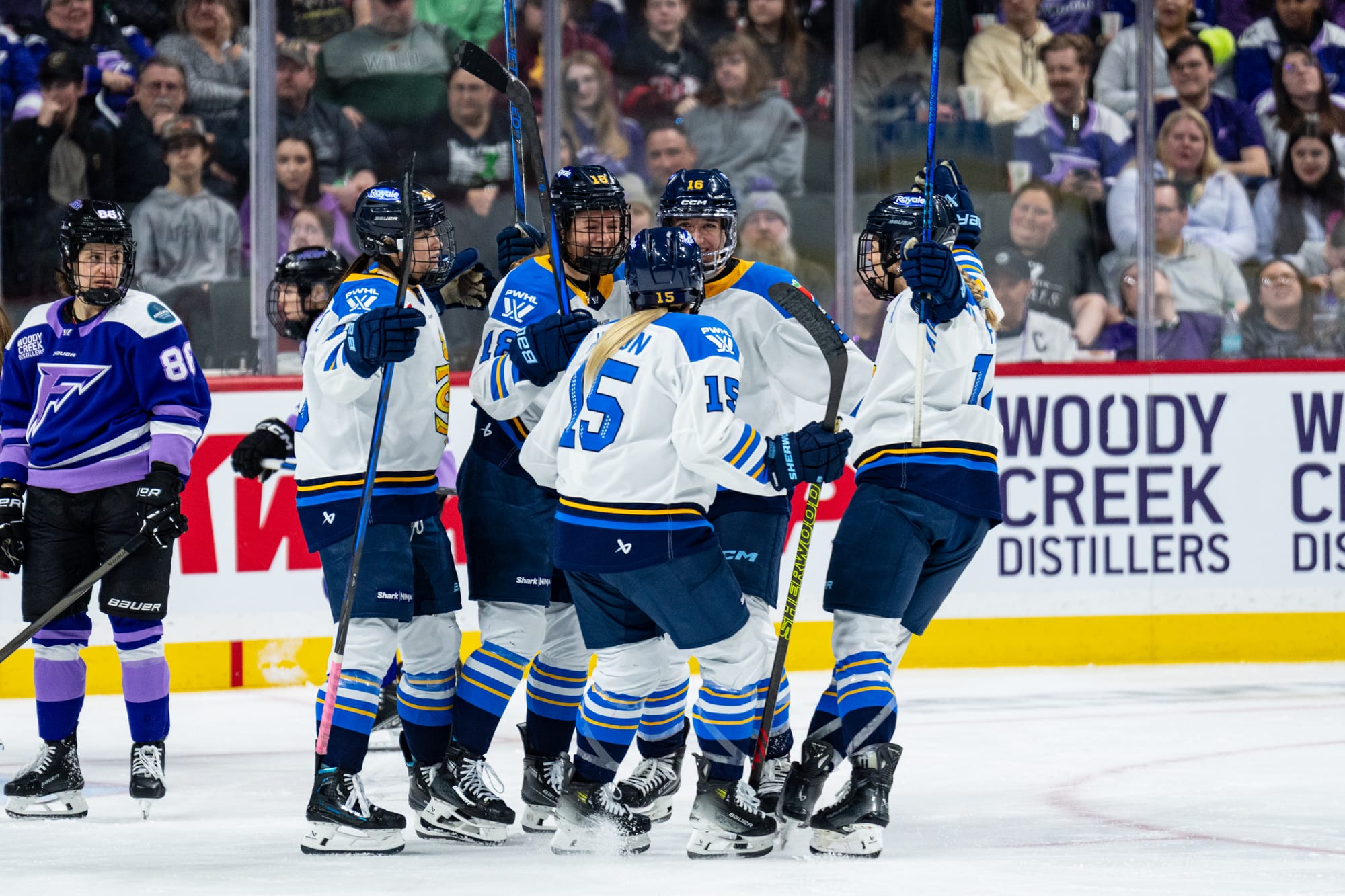 Five Sceptres players celebrate a goal with a group hug. They are wearing white away uniforms.