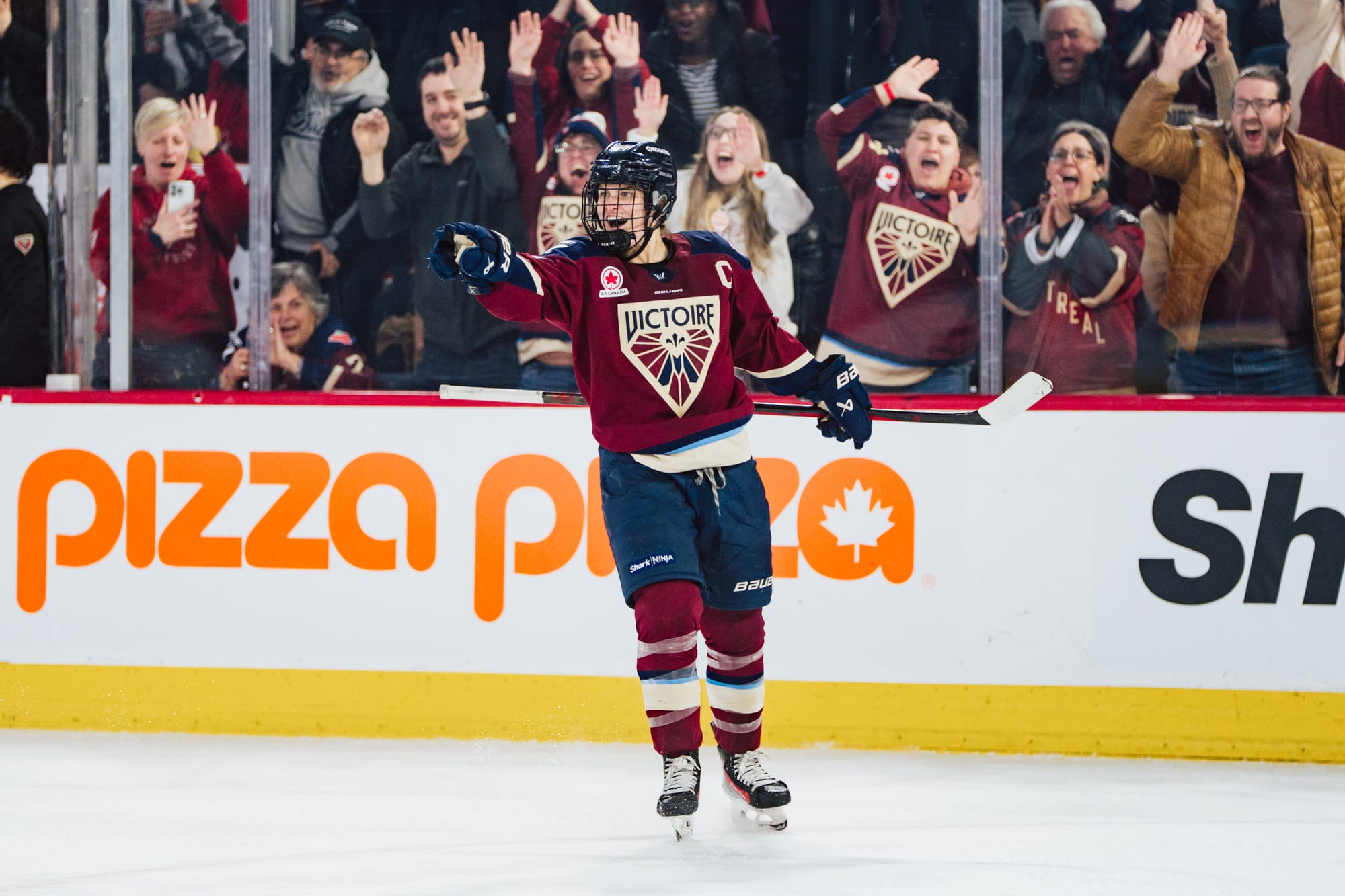 Poulin smiles and points to someone out of the frame. She is wearing a maroon home uniform.