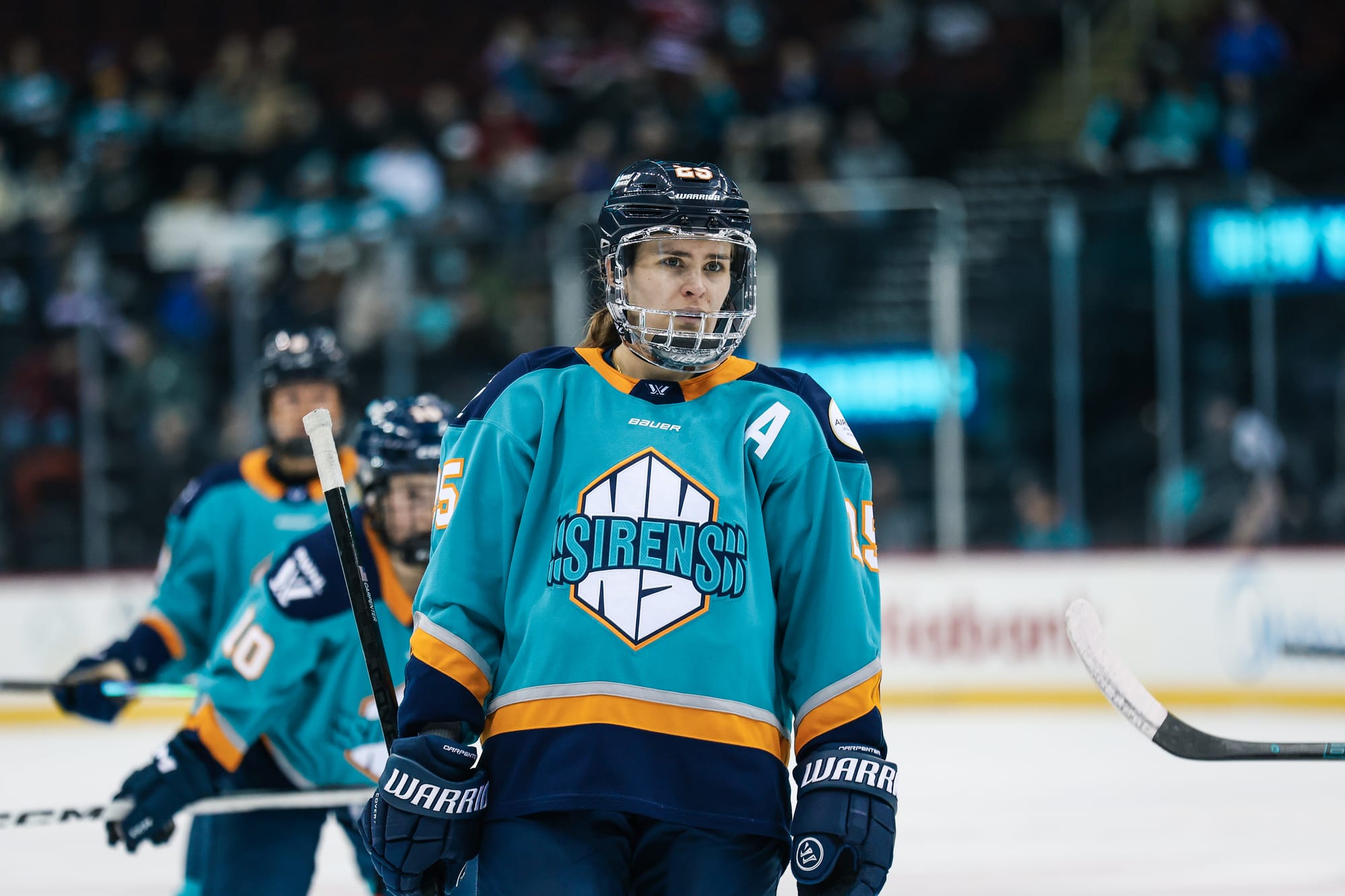 A waist-up shot of Carpenter as she stands at the faceoff dot. She is wearing a teal home uniform.