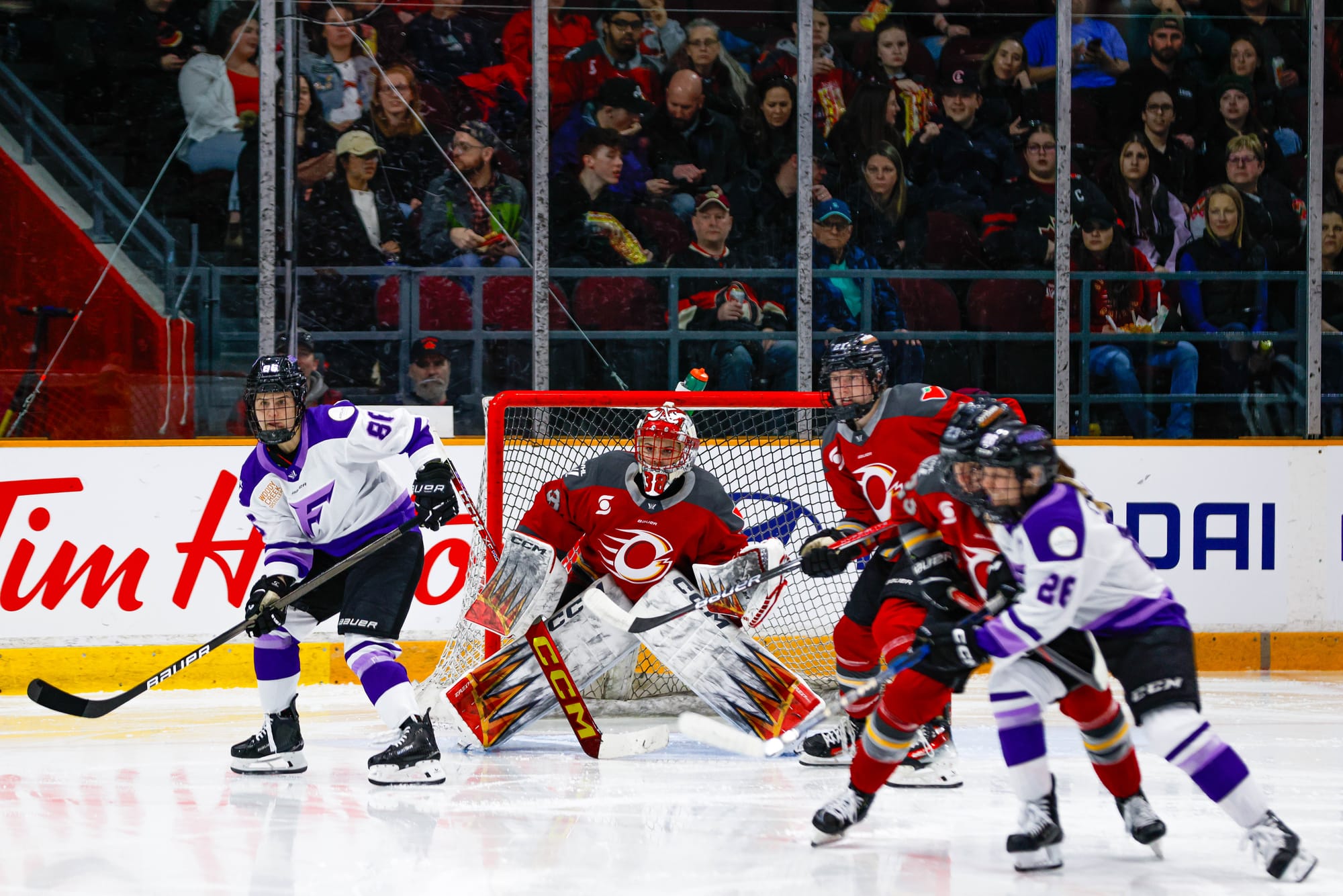 Maschmeyer searches for the puck as two Charge players battle with two Frost skaters. The Ottawa players are in red home uniforms, while the Frost are in white away ones.