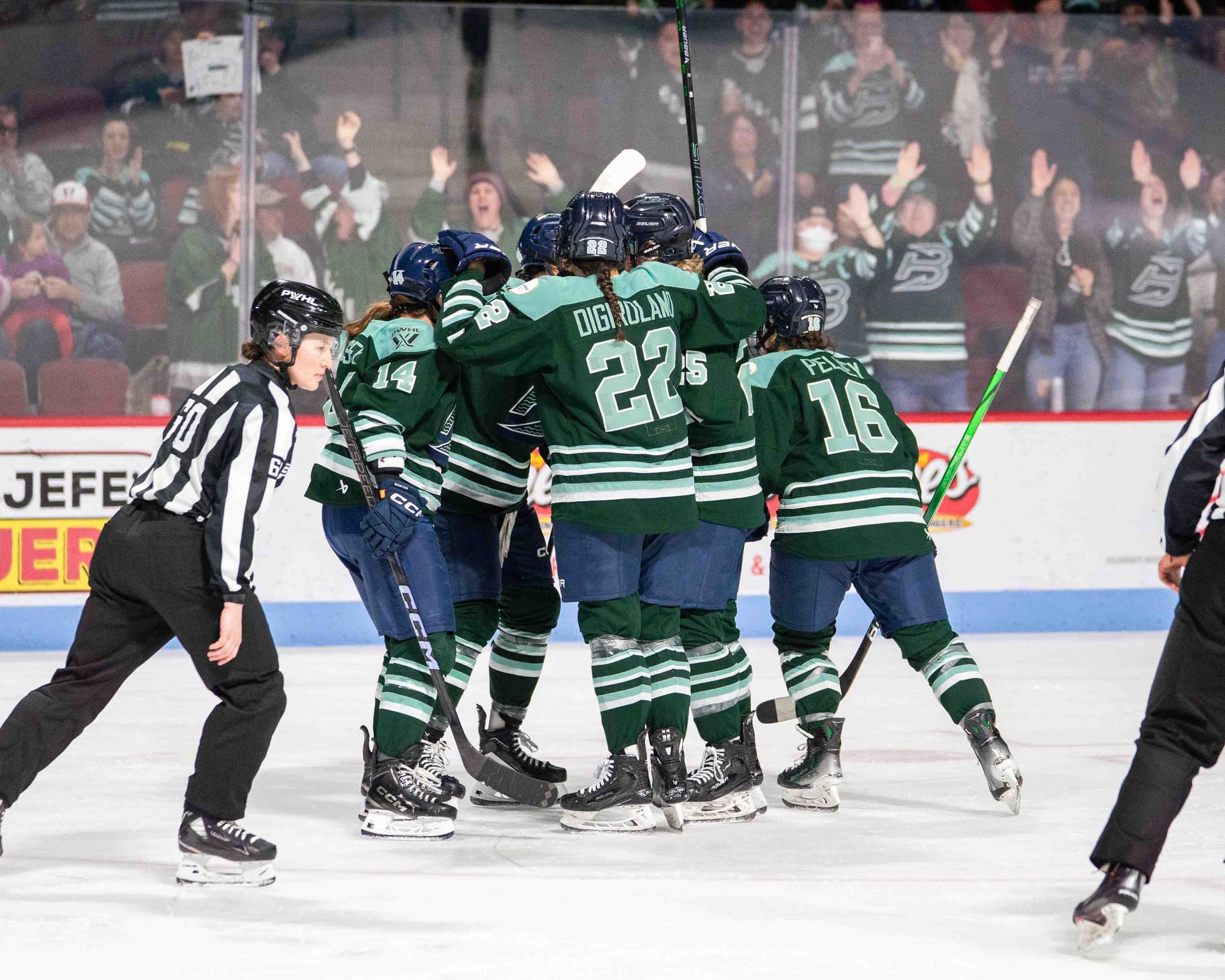 Fleet players celebrate with a tight group hug. They are wearing green home uniforms.