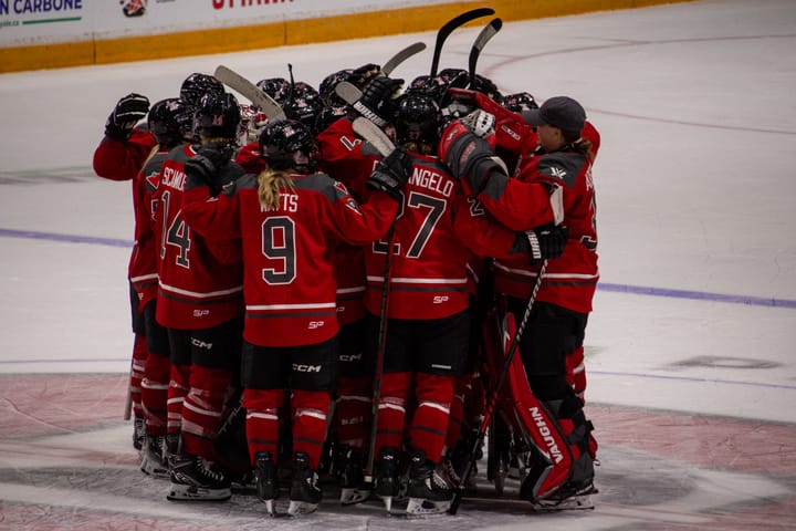 PWHL Ottawa does a group hug at centre ice.