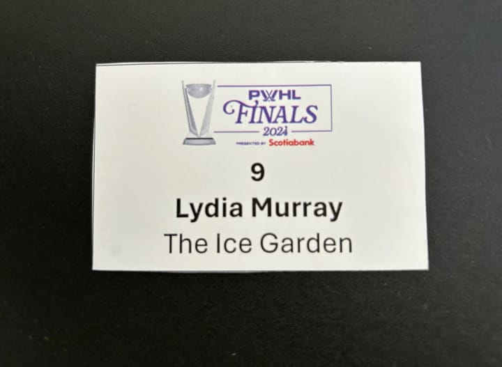 A small paper with the PWHL Finals logo. Underneath is 9, Lydia Murray, The Ice Garden (on separate lines).