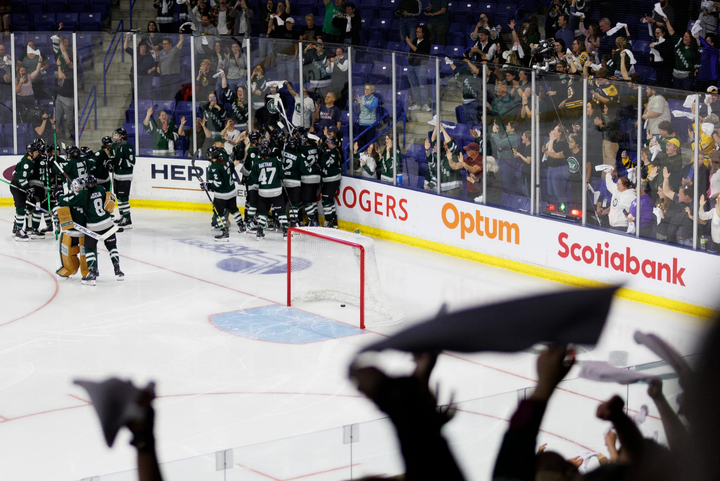 A wide shot of Boston celebrating with a group hug in the corner, while fans cheer in the stands all around them.
