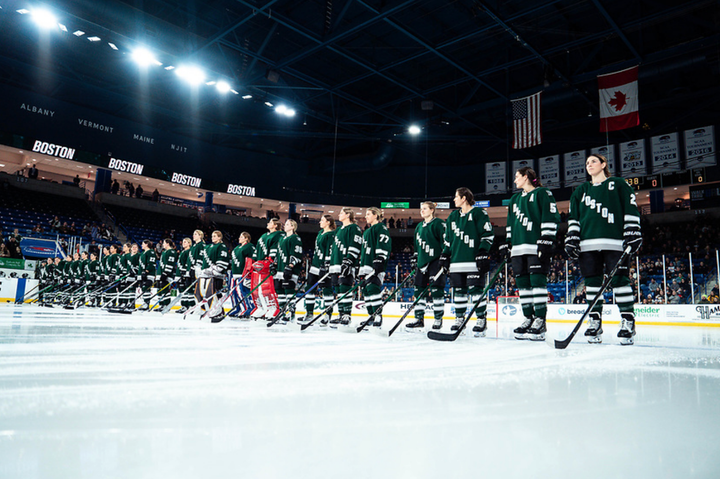 The whole Boston roster stands along the blue line, looking straight ahead while wearing green home jerseys.