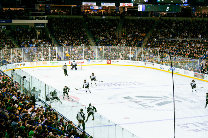 An above-ice level shot of Boston and Minnesota battling along the boards for the puck at the Tsongas Center.