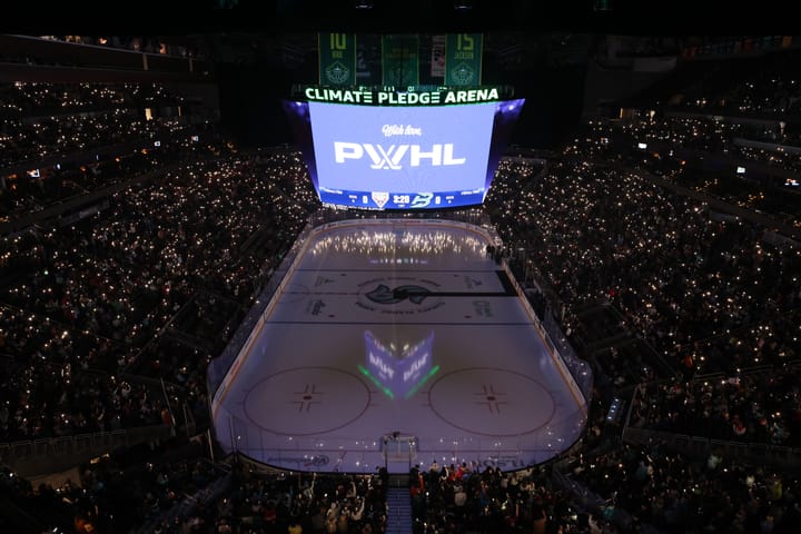 A shot from one end of the ice looking out over the ice and crowd. The lights are out and the fans have light-up wristbands.