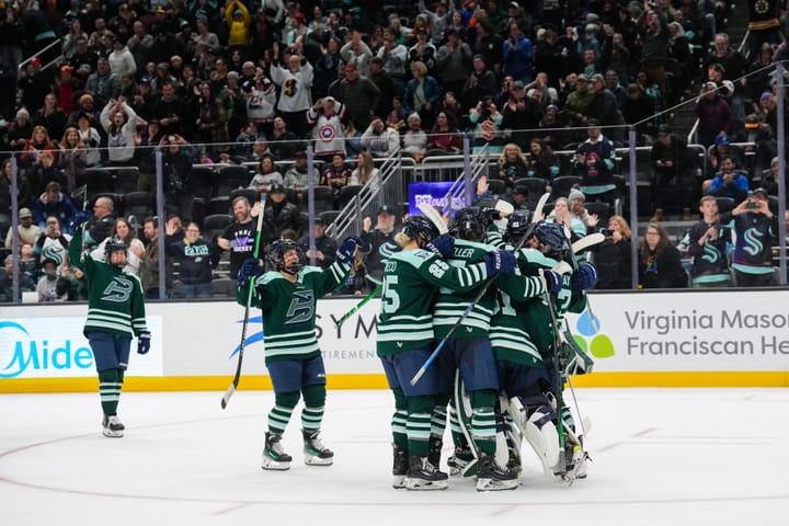 Fleet players celebrate with a tight group hug in one of the circles. They are wearing green home uniforms.