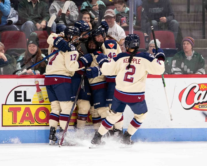 Montréal skaters celebrate with a group hug along the boards. They are wearing cream away uniforms.