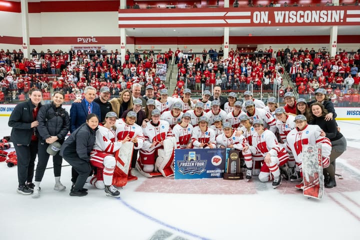 The Wisconsin Badgers gather on the ice for a photo in front of the crowd.